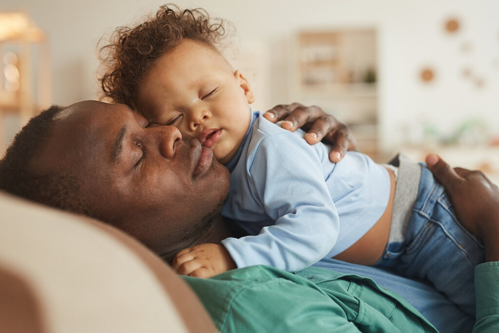 Father asleep with baby son